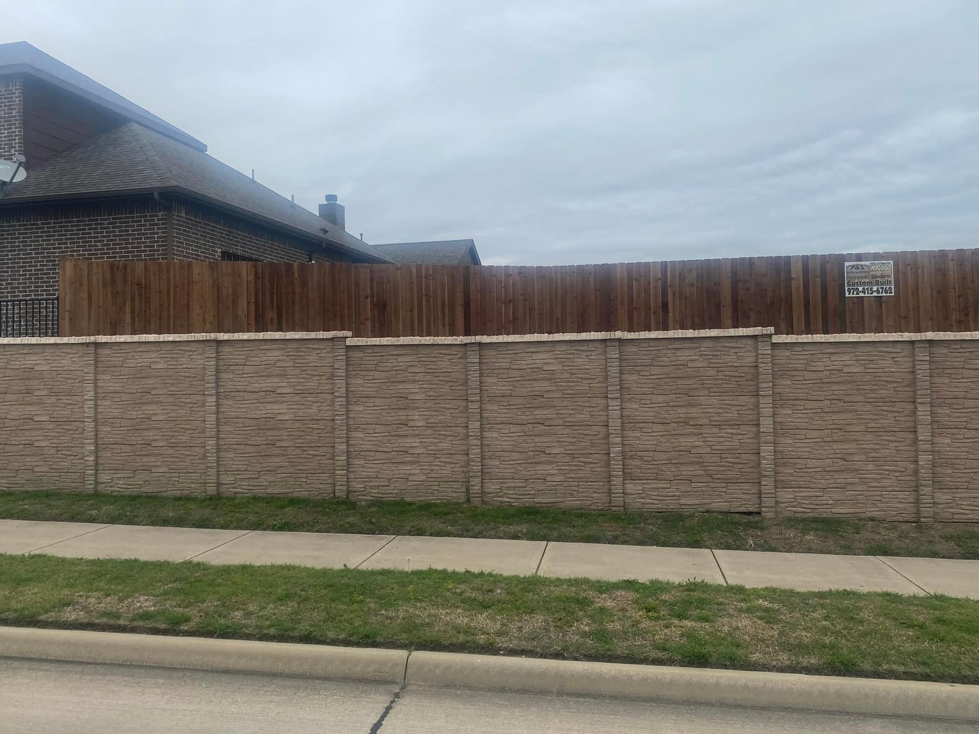 A brick wall with a wooden fence in front of a house.