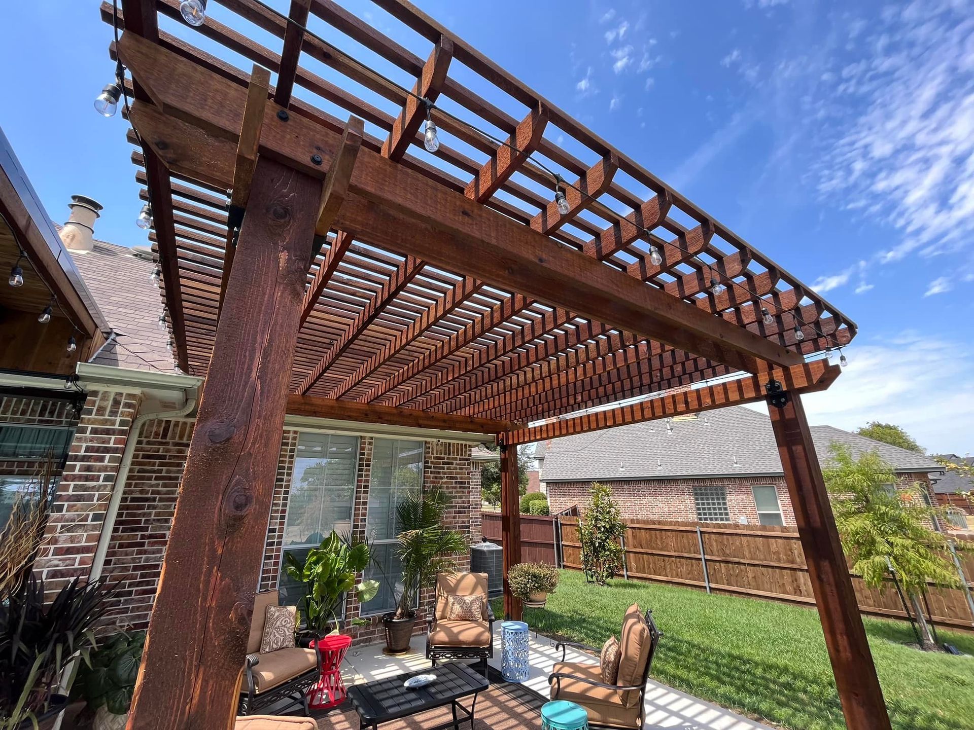 A wooden pergola is sitting in the backyard of a house.