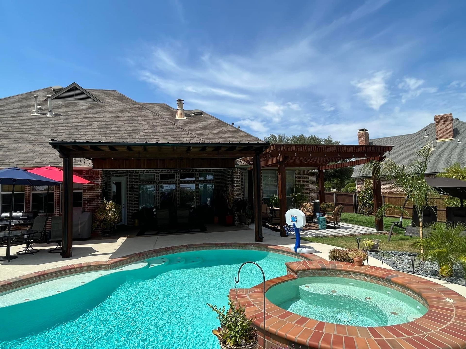 A large swimming pool with a hot tub in front of a house