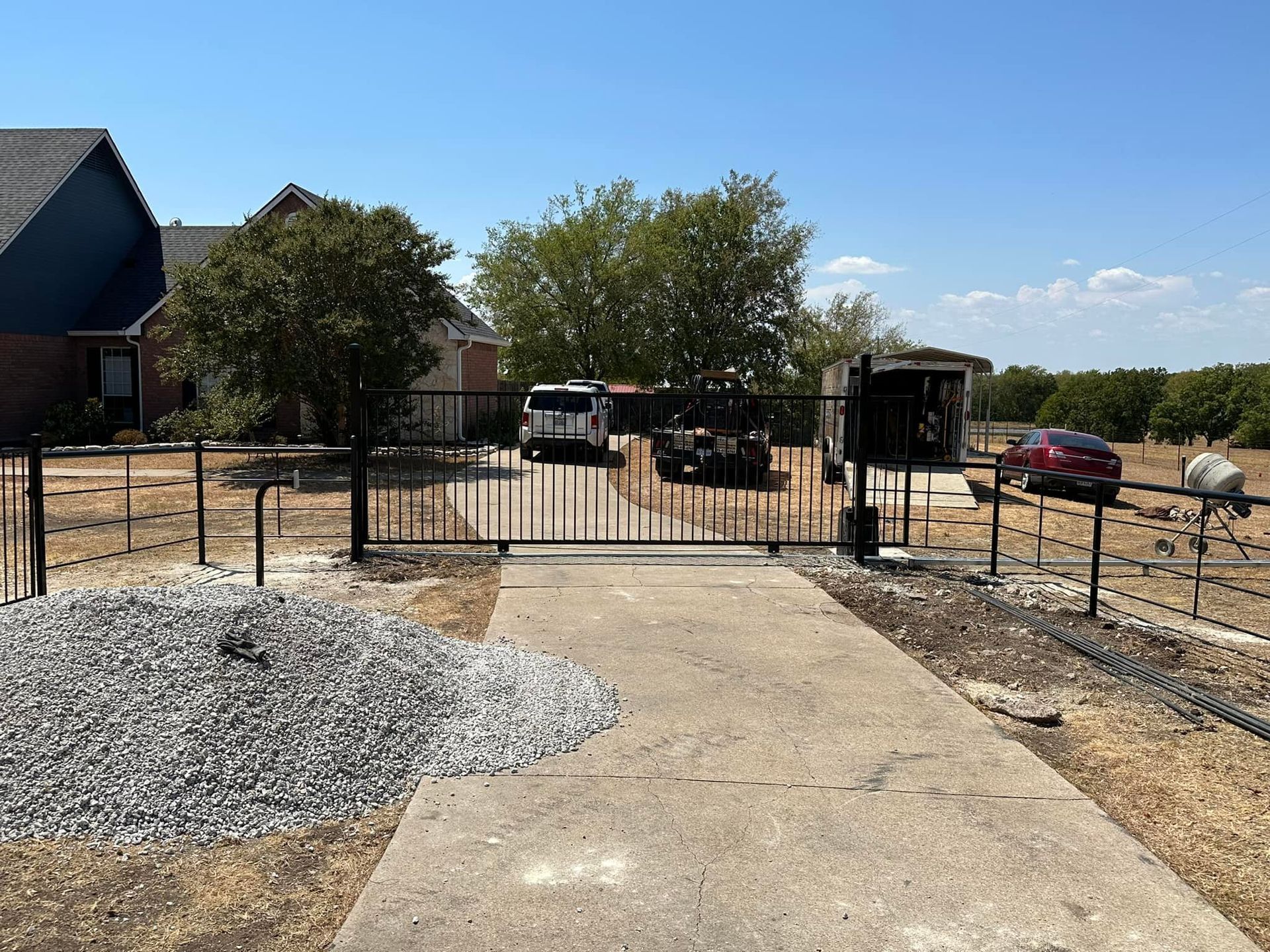A driveway with a fence and a gate leading to a house.