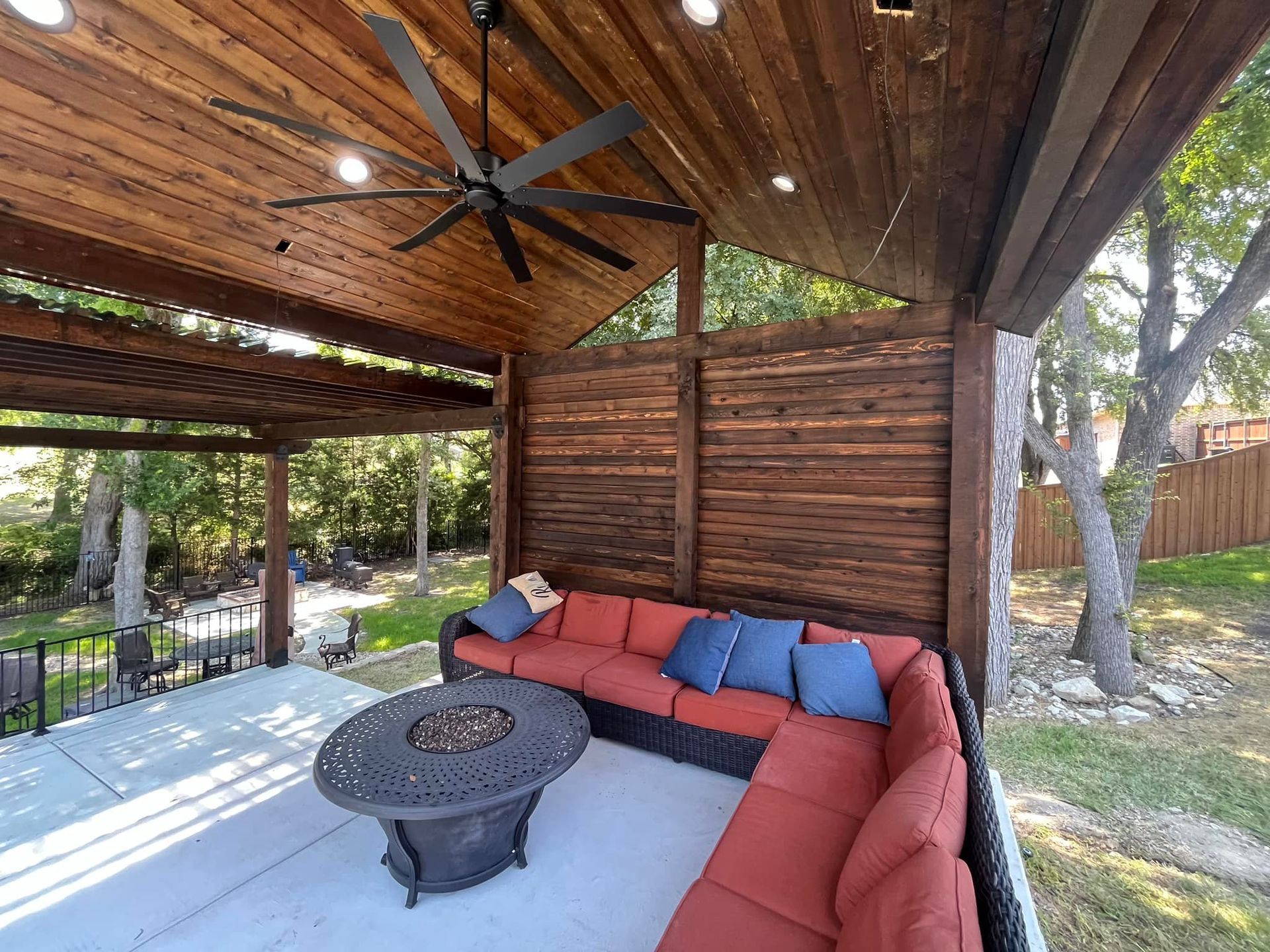 A patio with a couch , table , and ceiling fan.