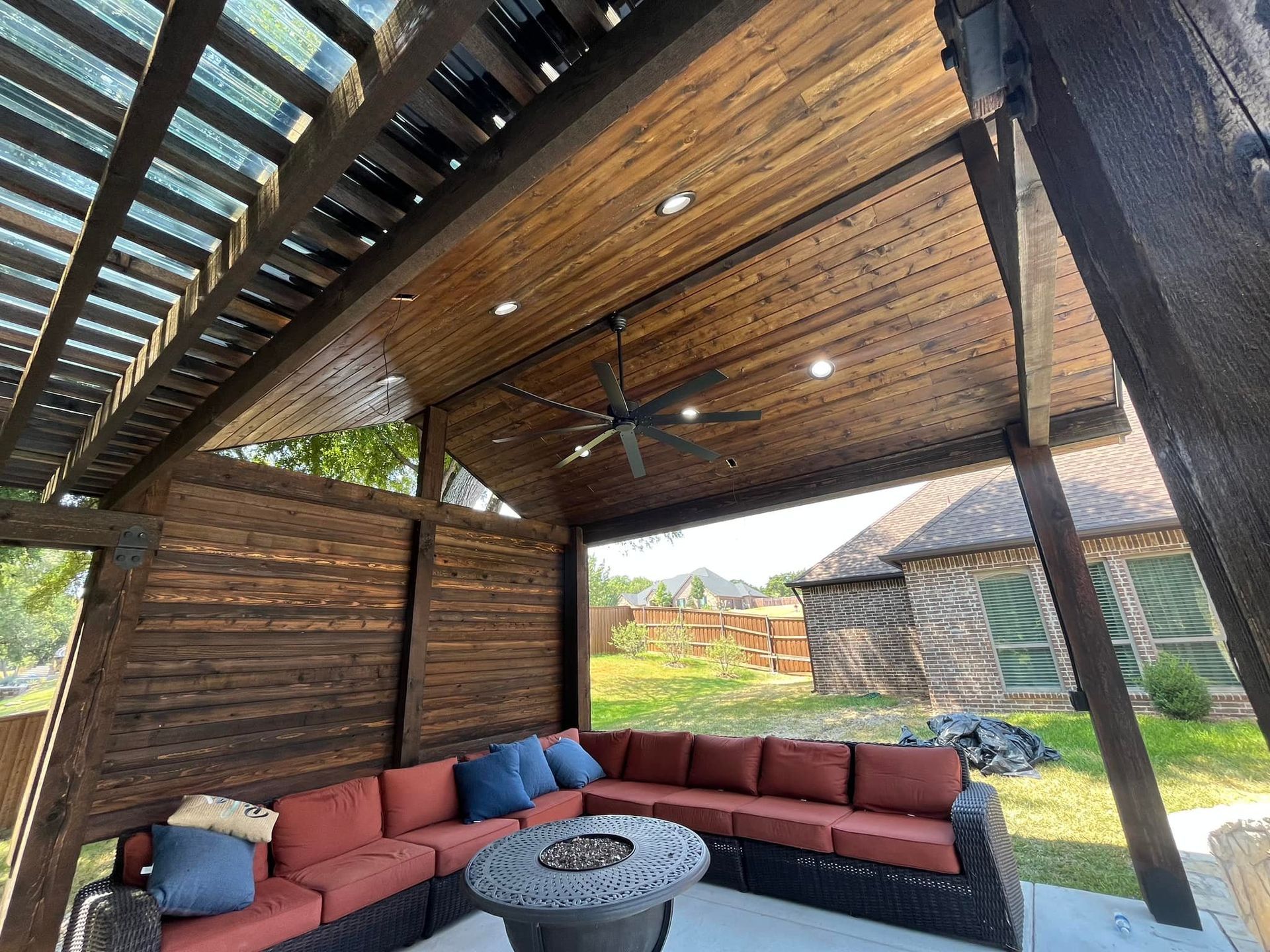 A patio with a couch and a fire pit under a pergola.