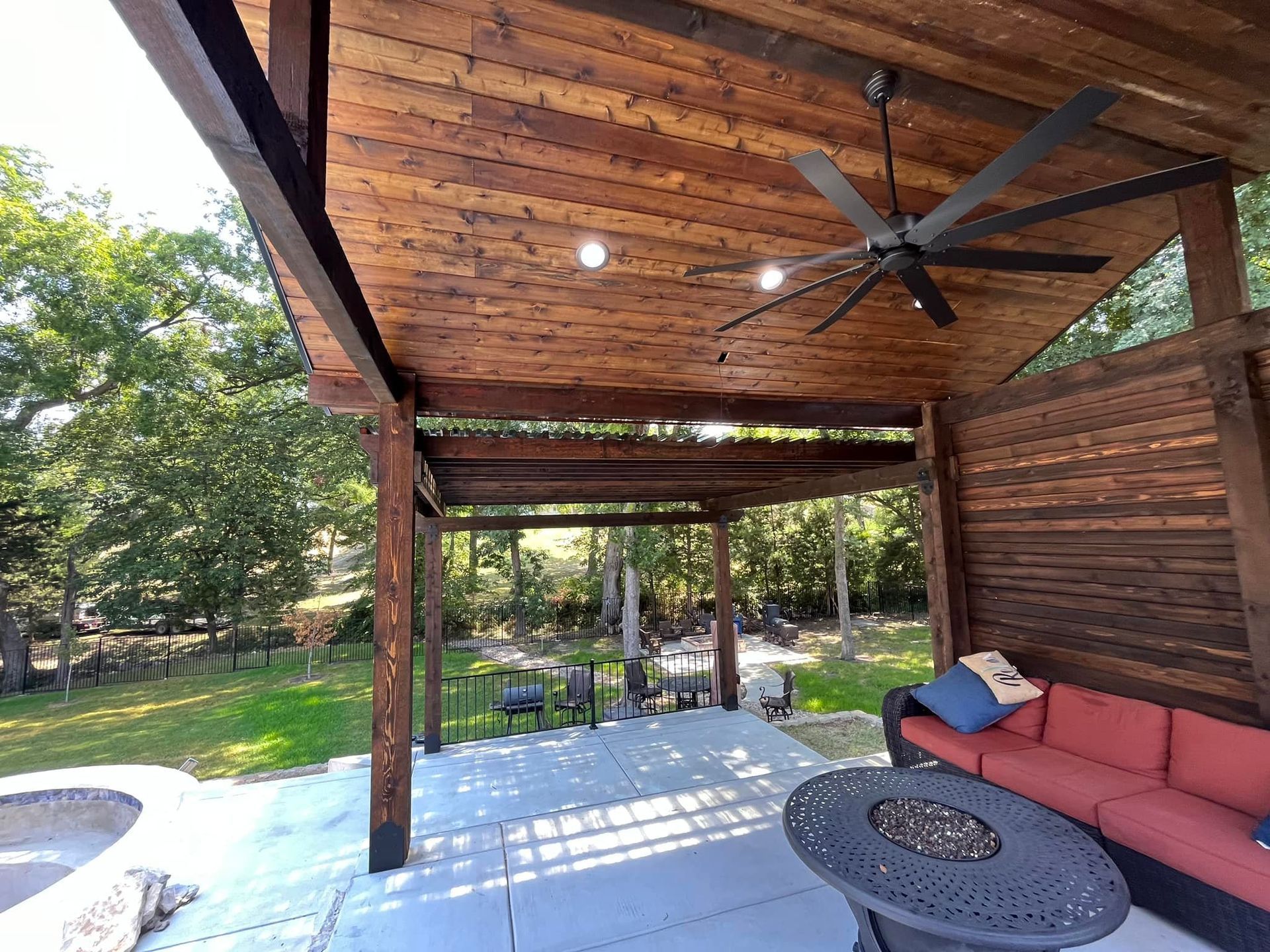 A patio with a couch , table , and ceiling fan.