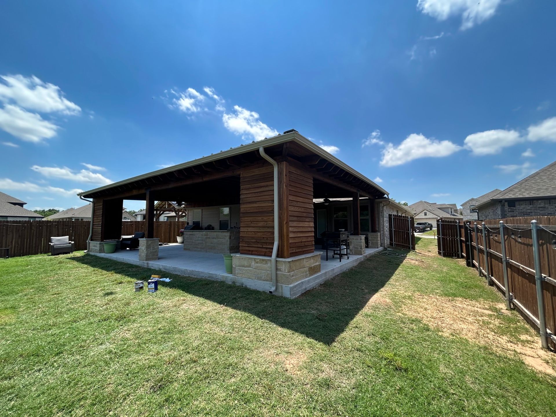 The backyard of a house with a pavilion and a fence.