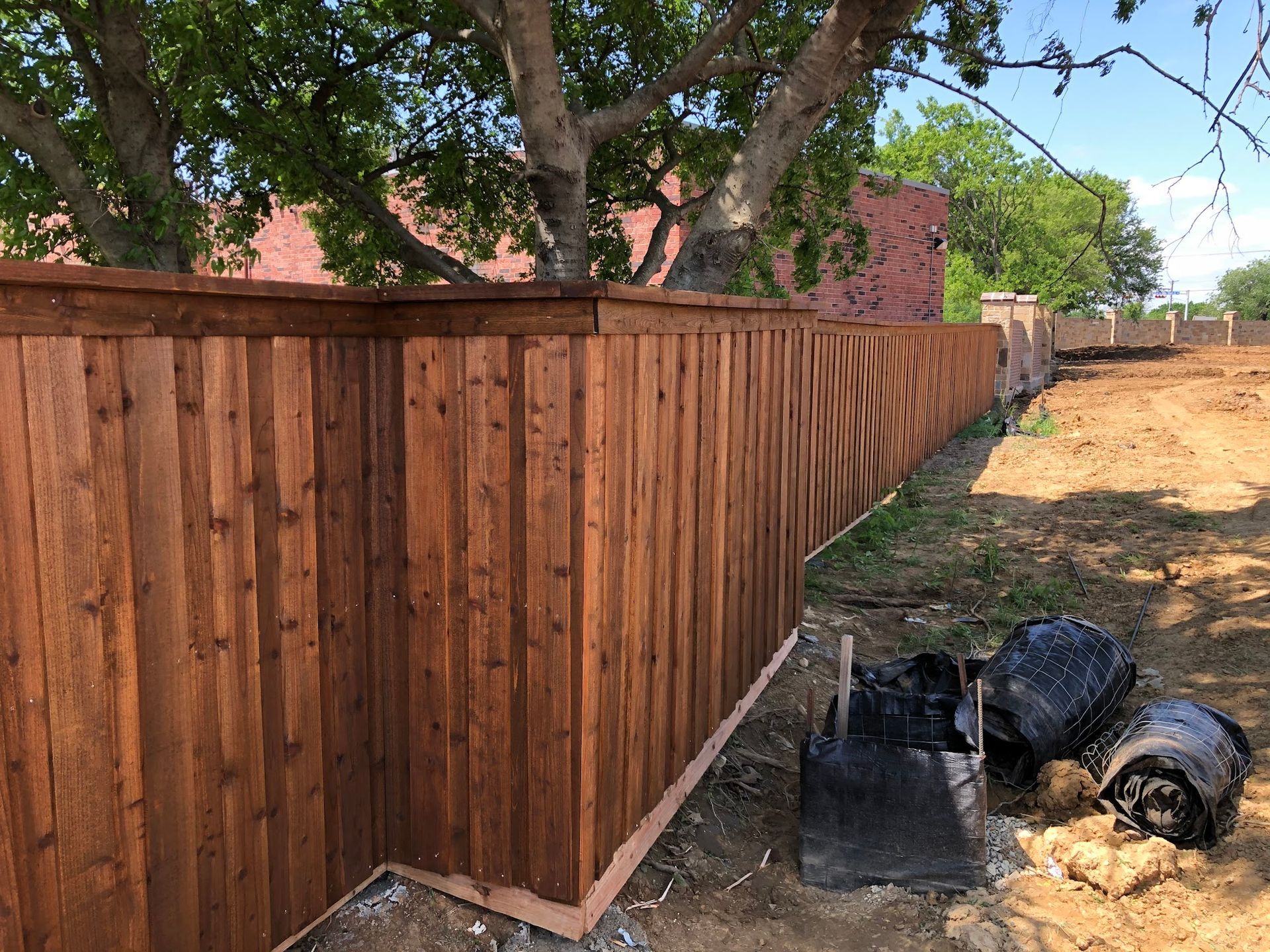 A wooden fence is being built in a dirt field.
