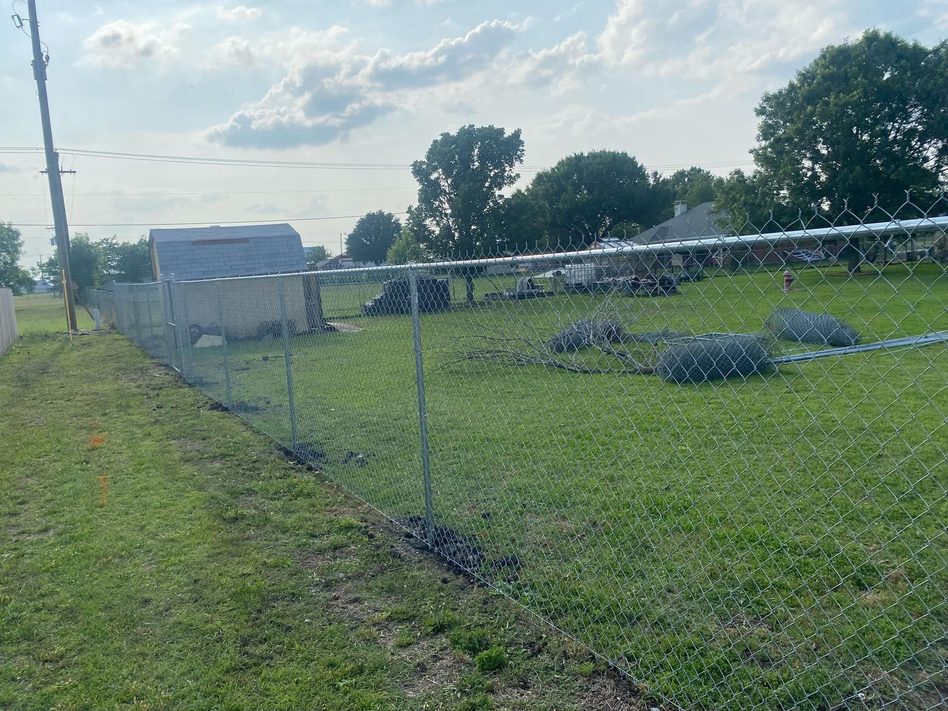 A chain link fence surrounds a grassy field.