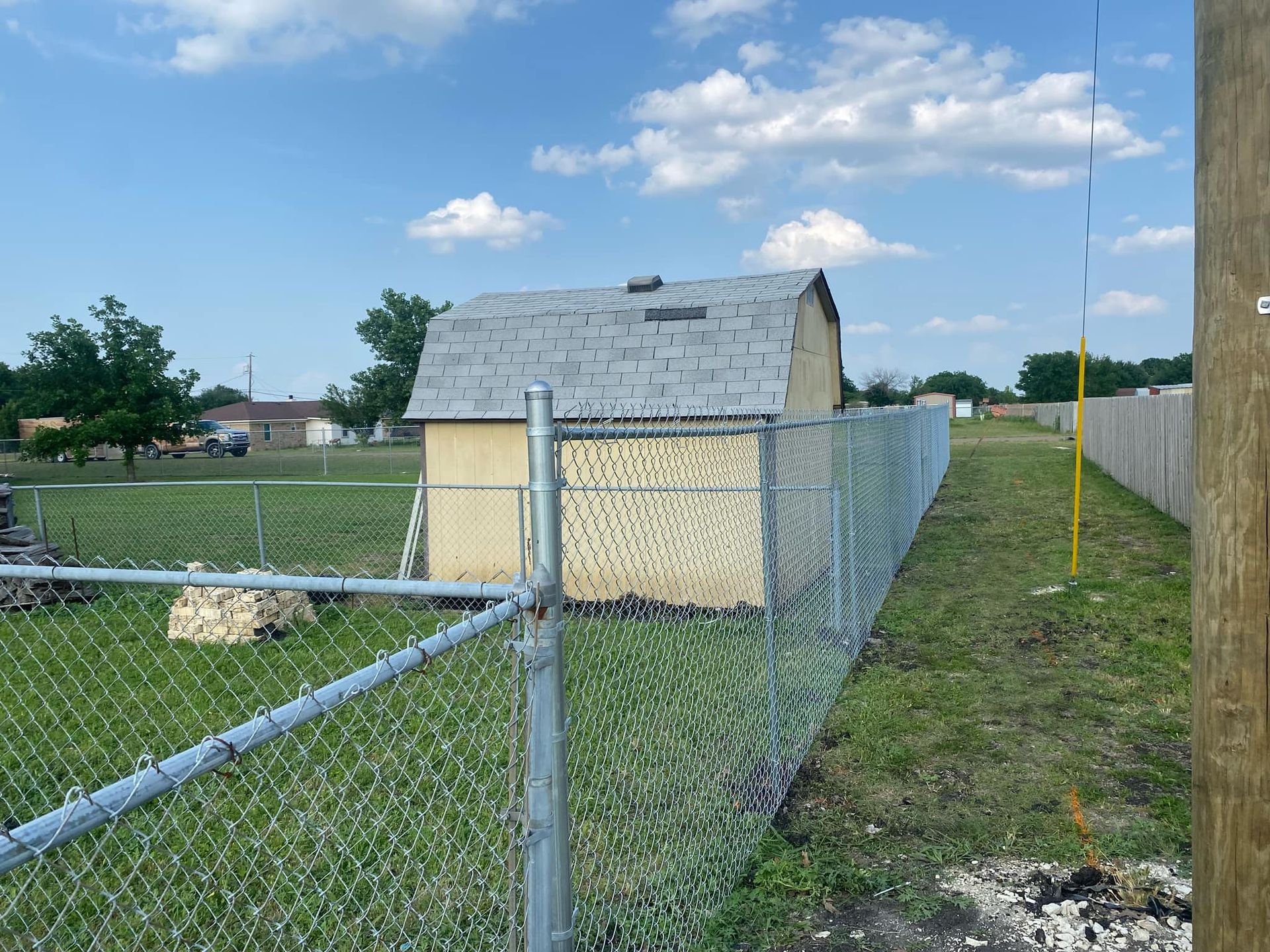 A chain link fence with a shed in the background