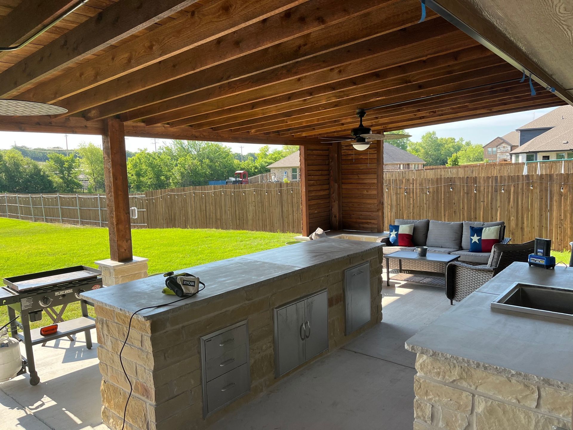 A patio with a large island and a couch under a wooden roof.