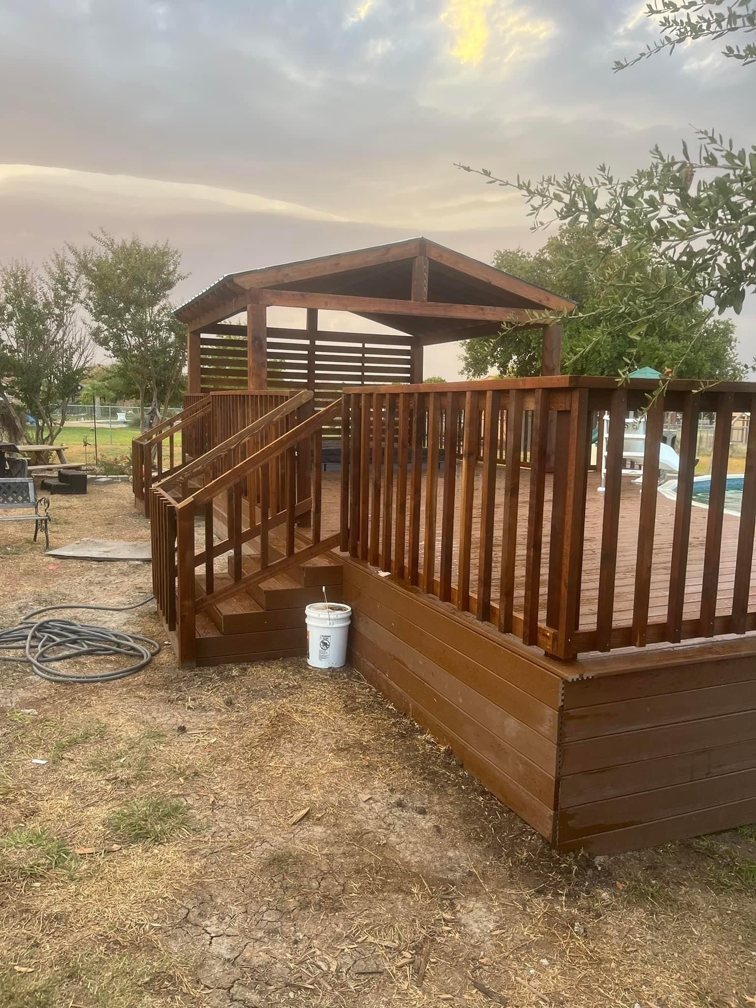 A wooden deck with stairs and a gazebo in the background.