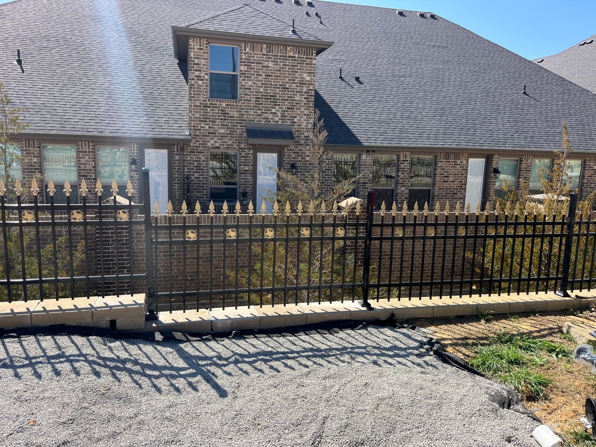 A large brick house with a black fence in front of it.