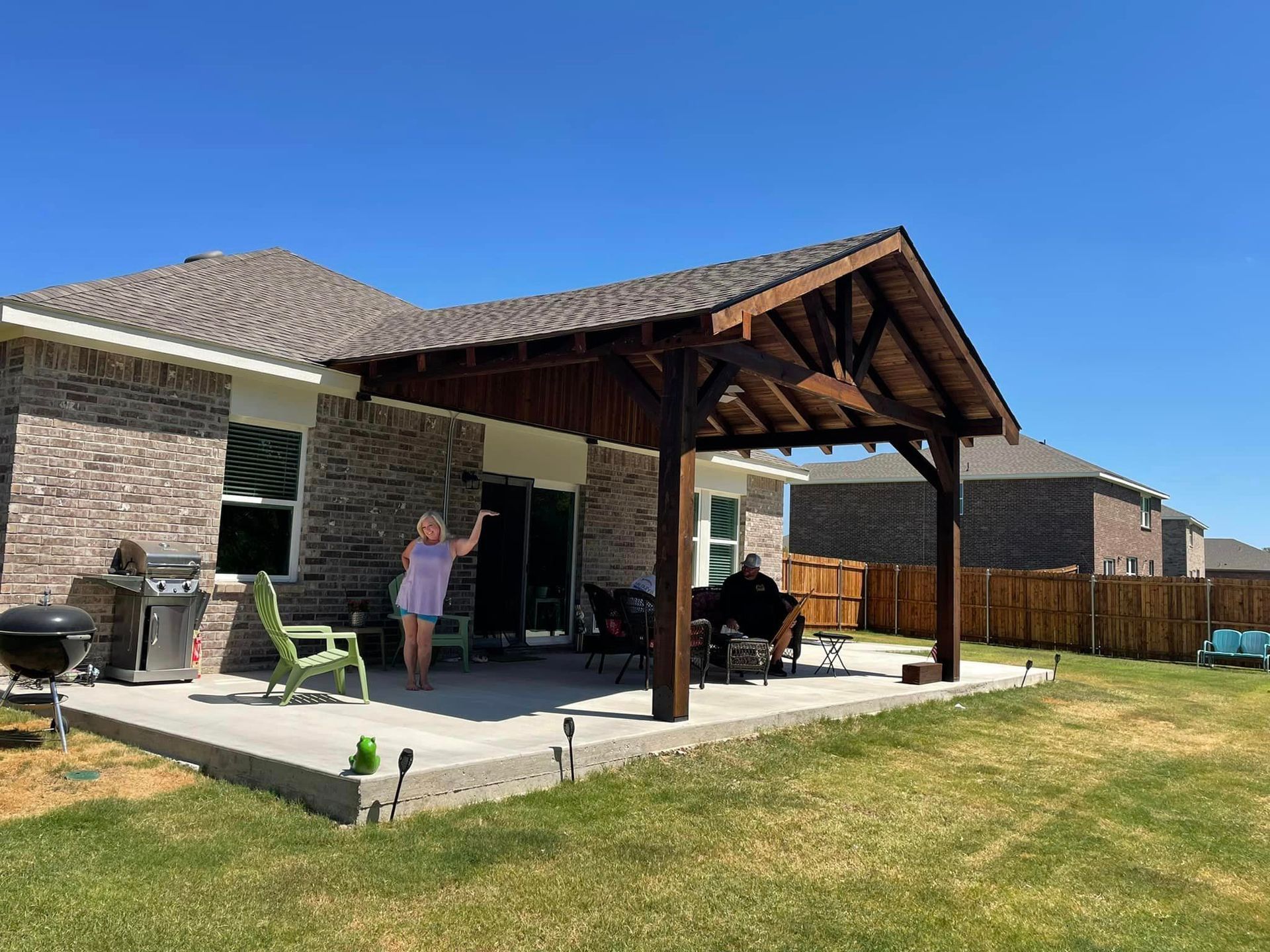 A woman is standing on a patio in front of a house.