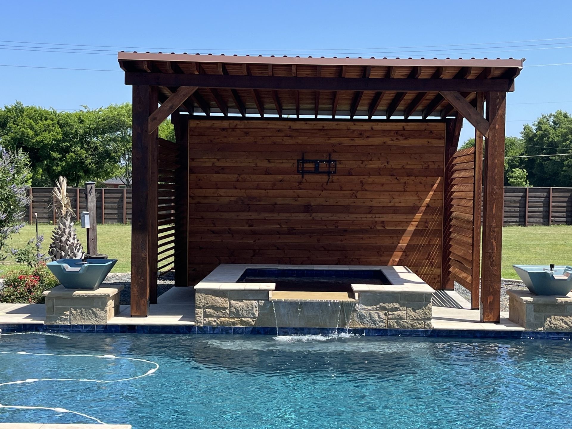 A large swimming pool with a wooden pergola over it