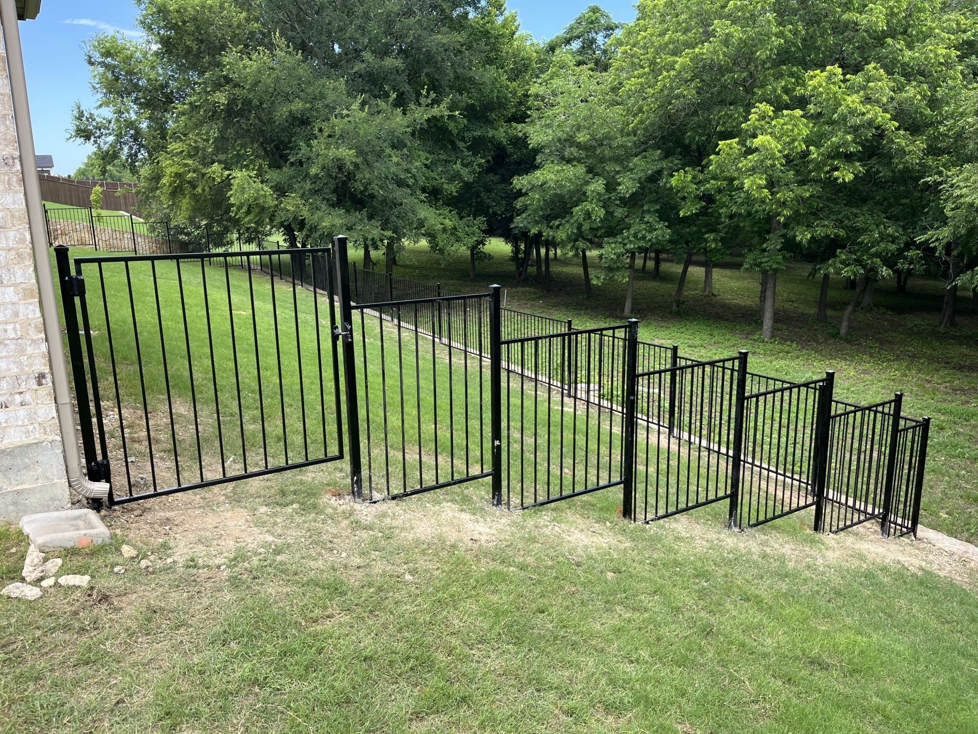 A black metal fence surrounds a lush green field.