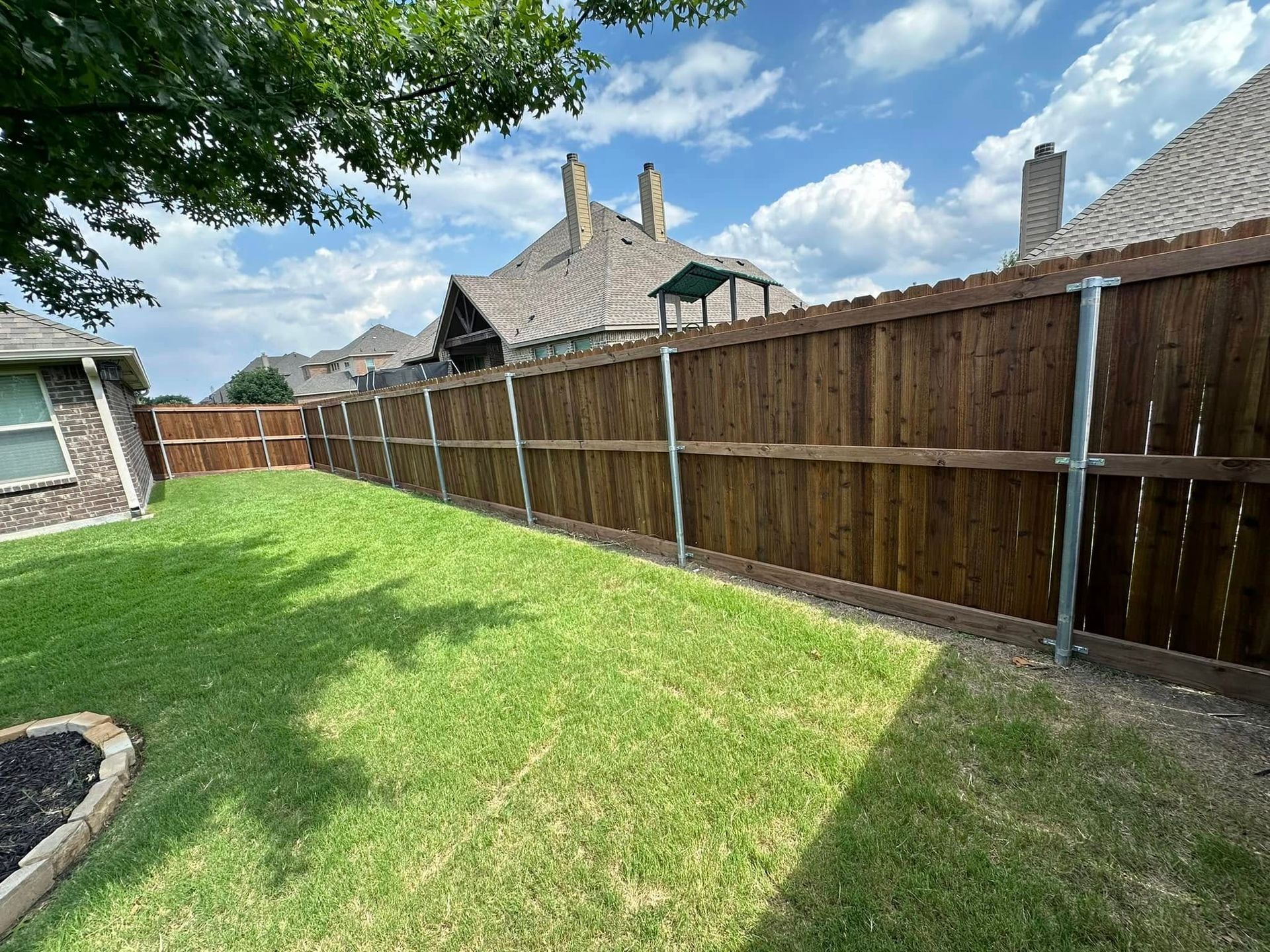 There is a wooden fence in the backyard of a house.