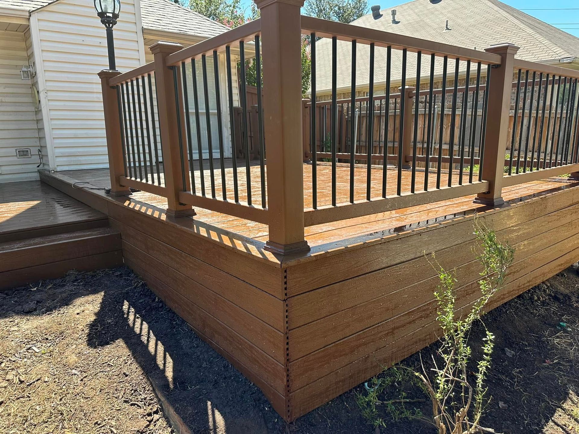 A wooden deck with a metal railing in front of a house.