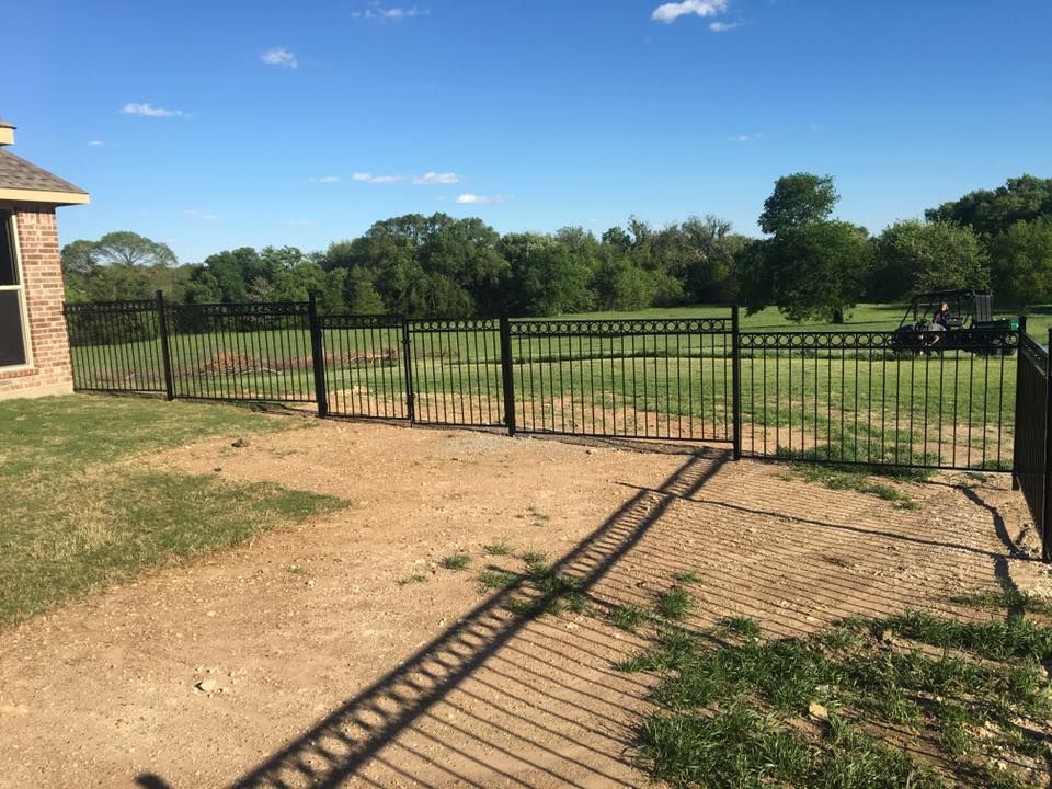 A black wrought iron fence surrounds a golf course.