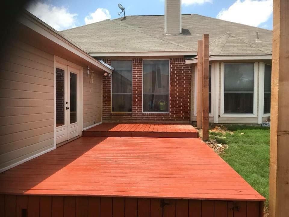 A wooden deck is sitting in front of a brick house.