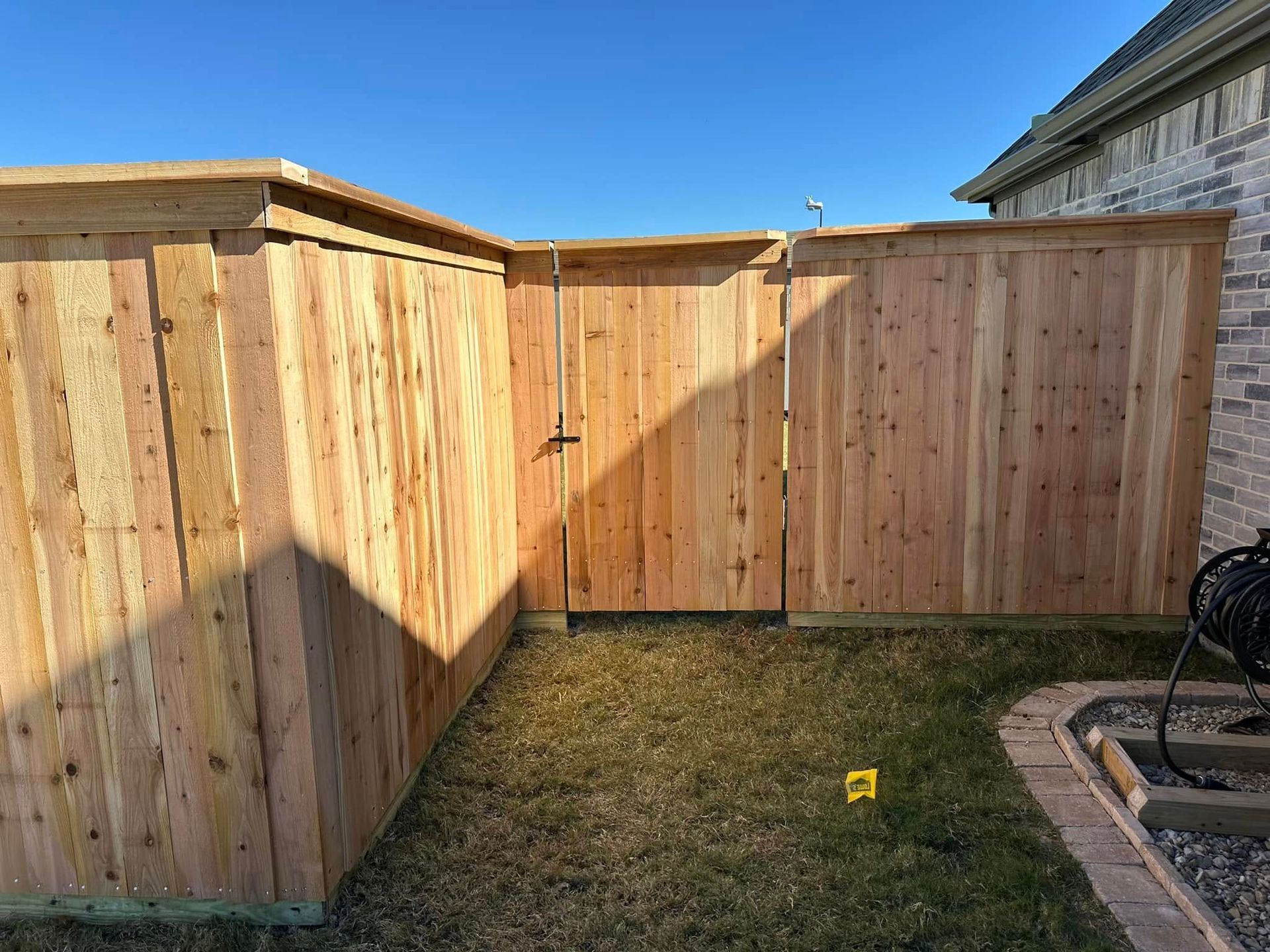 A wooden fence with a gate in the backyard of a house.