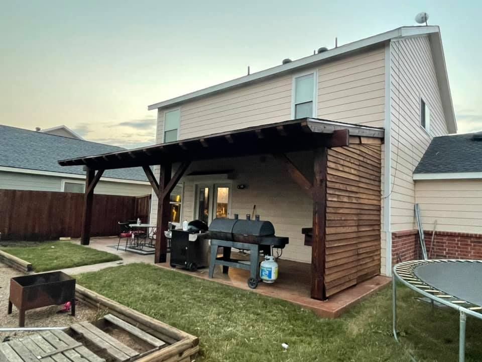 A house with a pergola and a grill in the backyard.