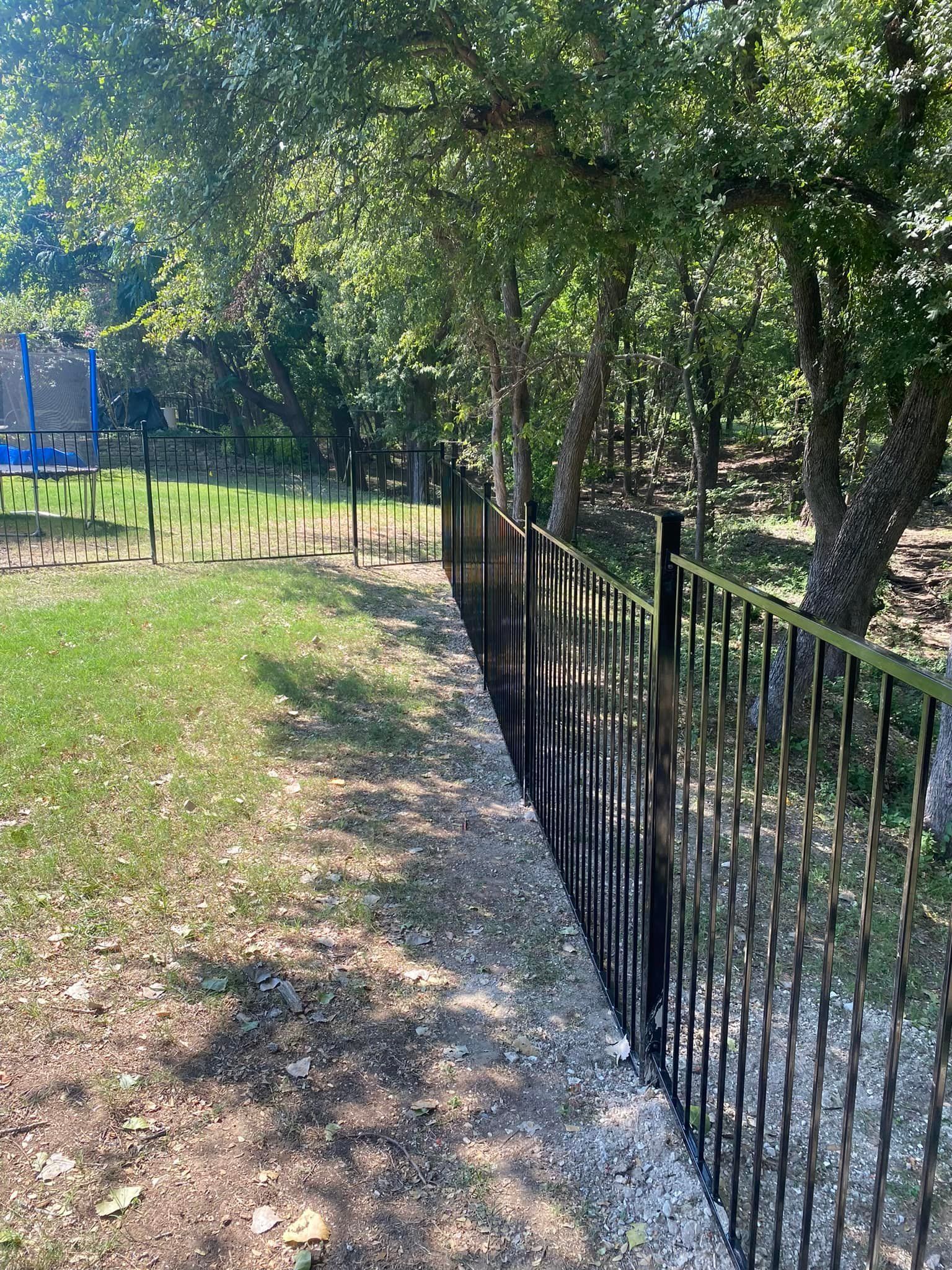 A wrought iron fence surrounds a lush green field.