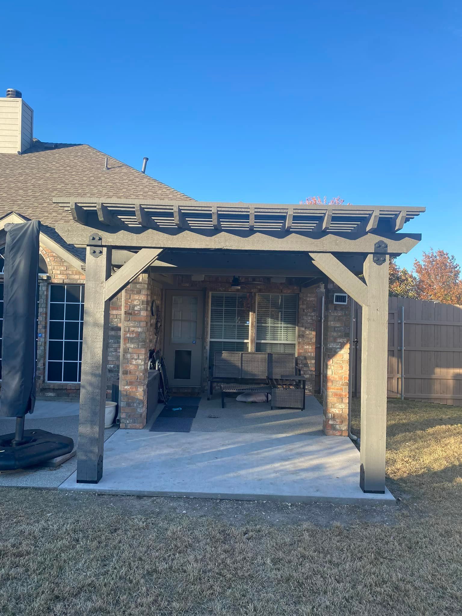 There is a pergola in the backyard of a house.
