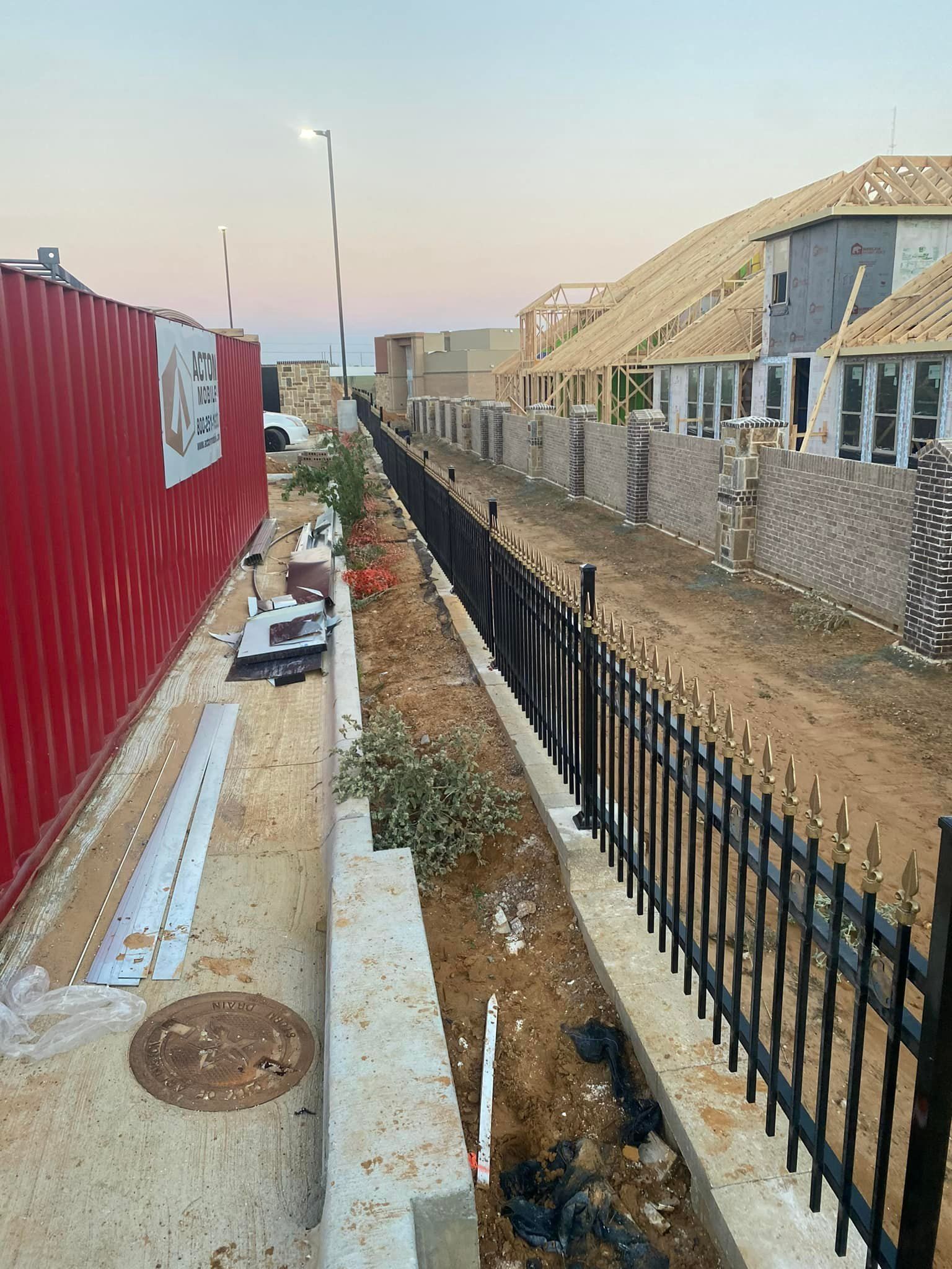 A fence is surrounding a construction site with a lot of buildings in the background.