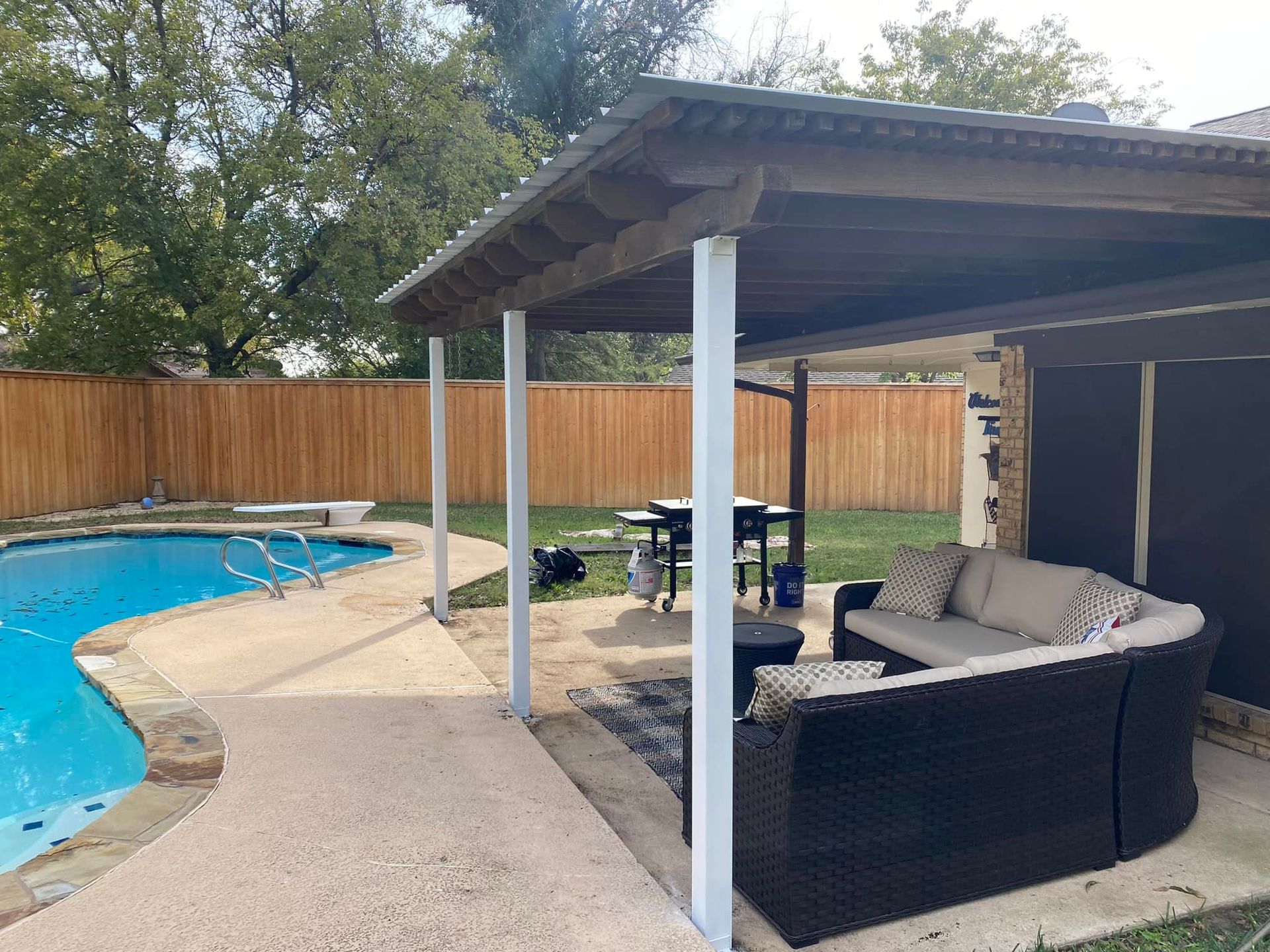 A patio area with a couch , table and chairs next to a pool.