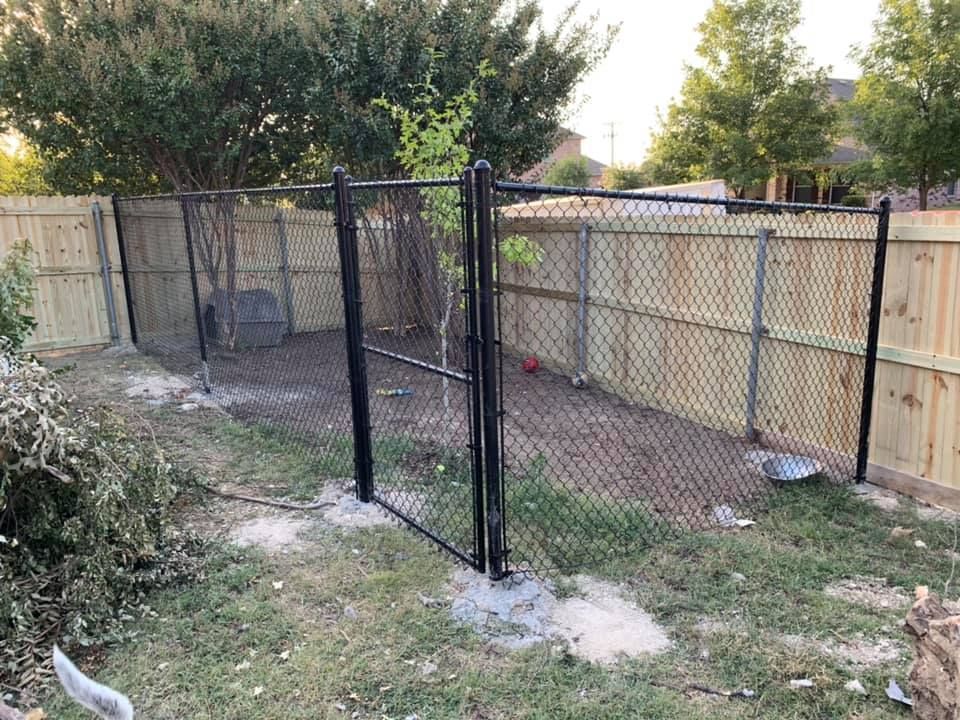 A chain link fence with a wooden fence behind it in a backyard.