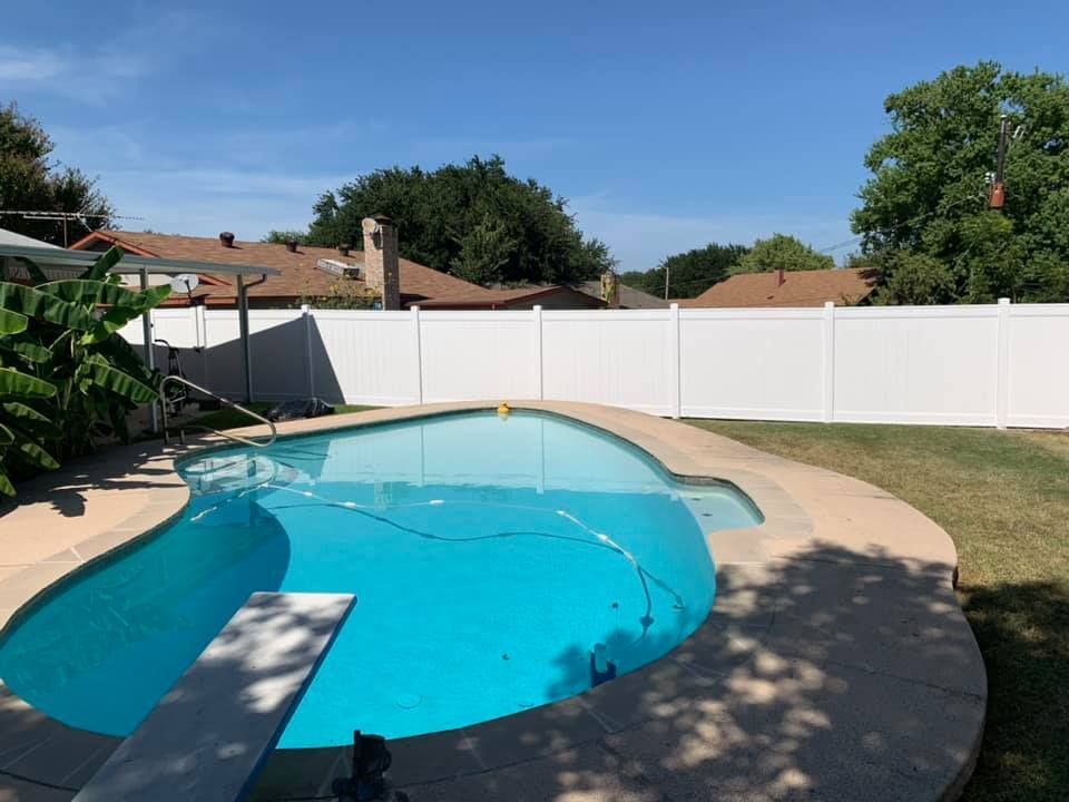 A large swimming pool with a white fence surrounding it.