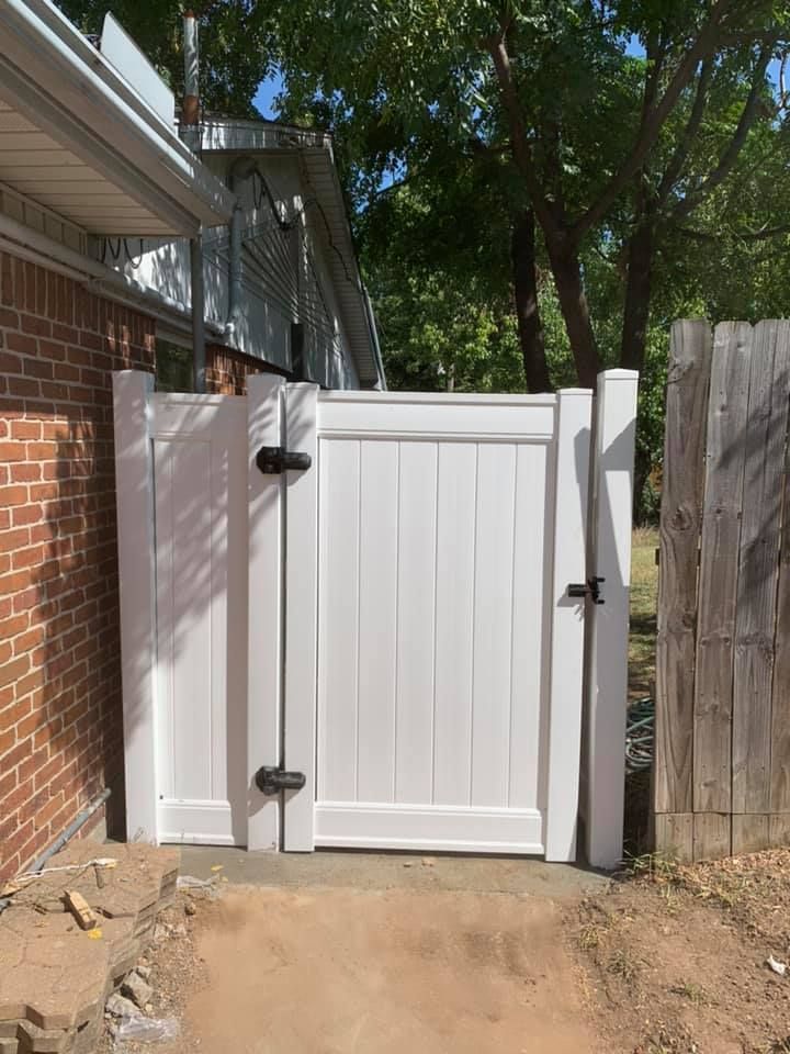 A white gate is sitting next to a brick building.