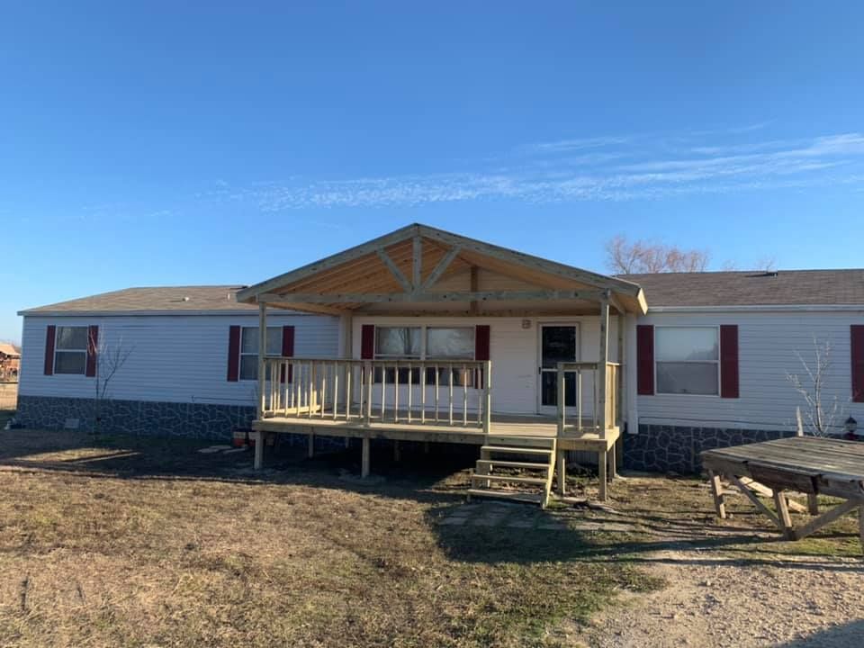 A mobile home with a large porch and stairs.