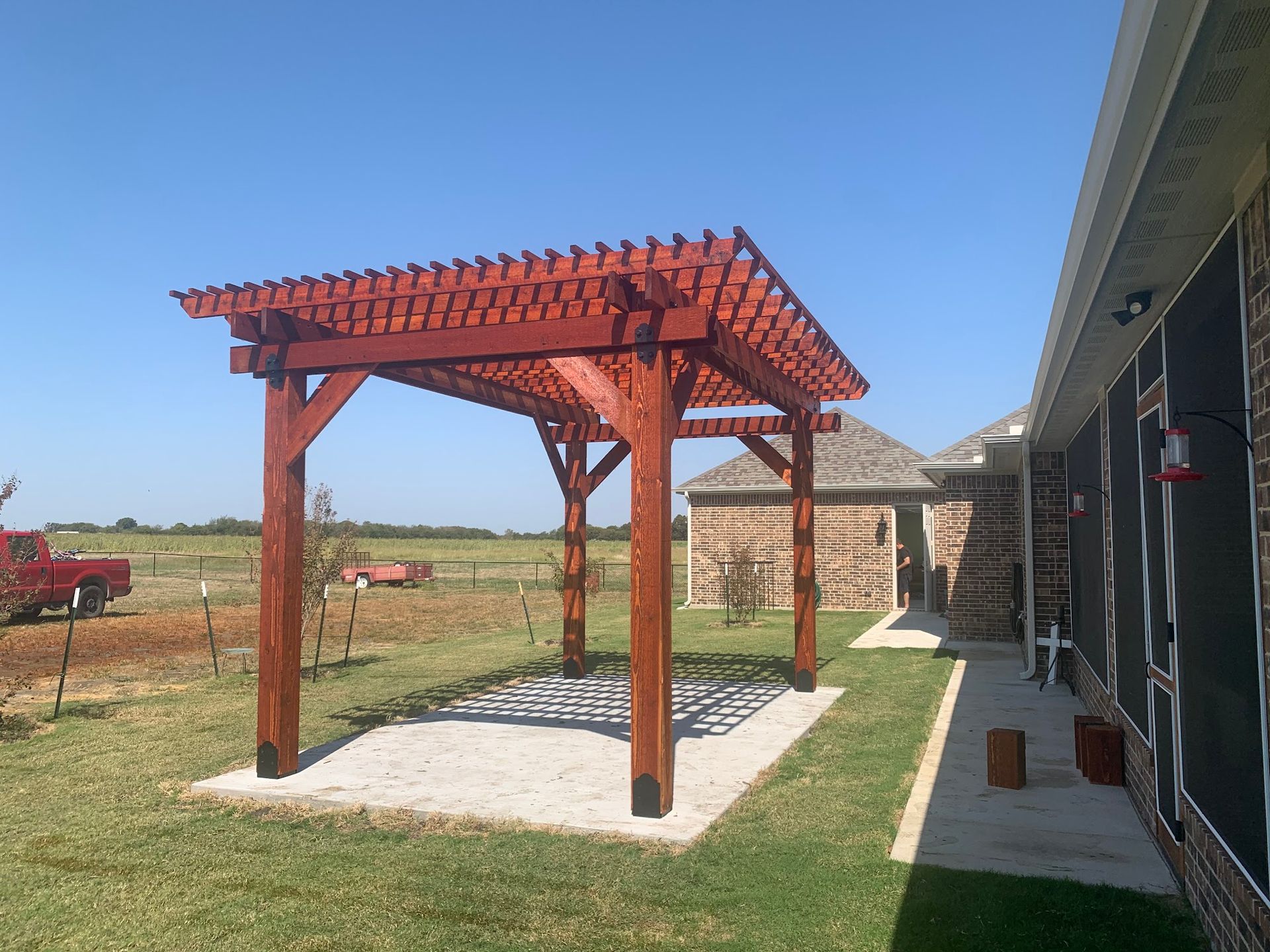 A wooden pergola is in the backyard of a house.