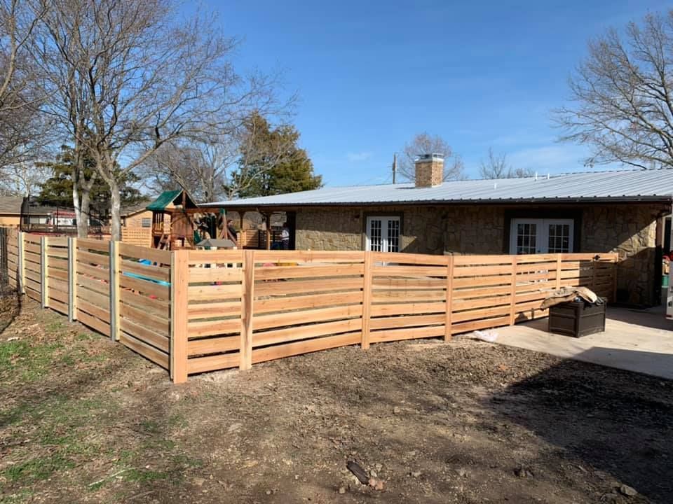 A wooden fence is surrounding a backyard of a house.