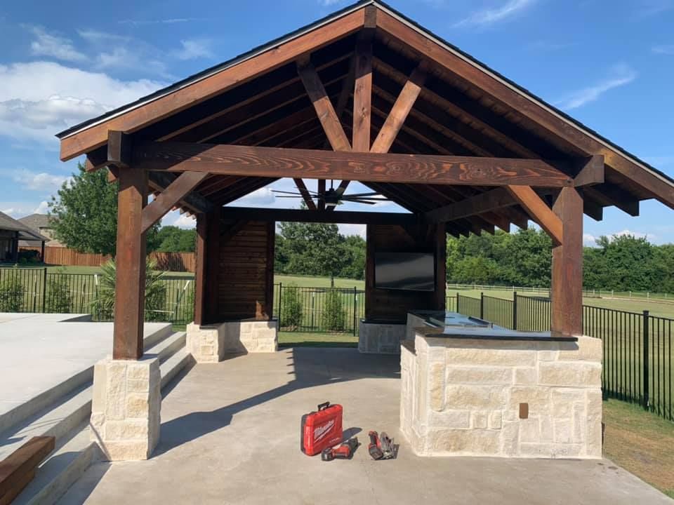 A wooden pavilion with a kitchen and a tv on it