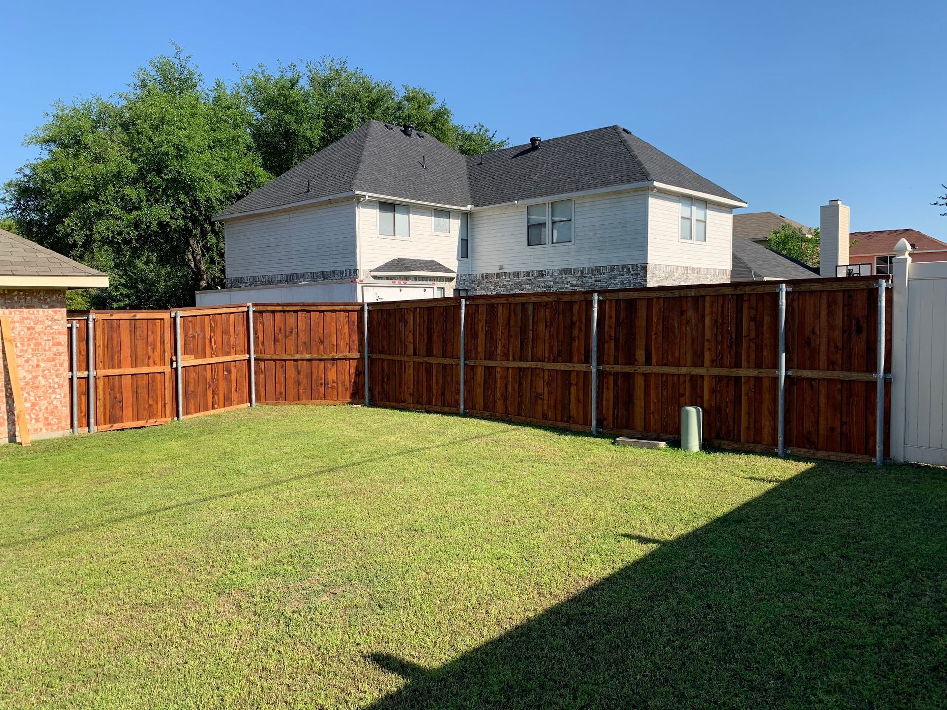 There is a wooden fence in the backyard of a house.