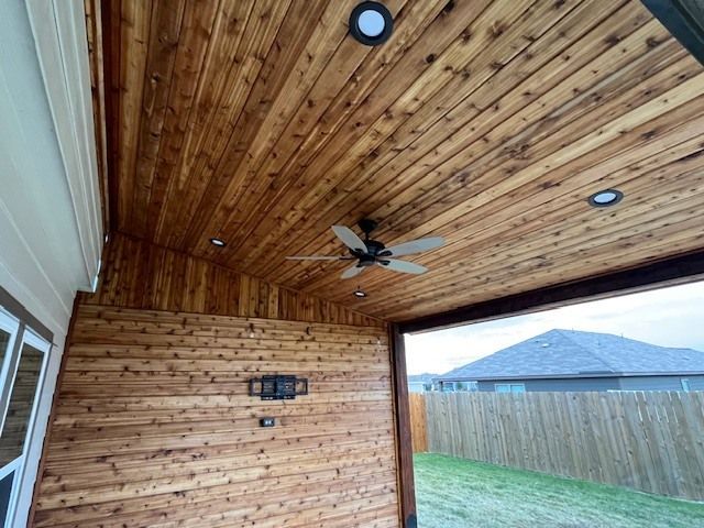 A porch with a wooden ceiling and a ceiling fan.