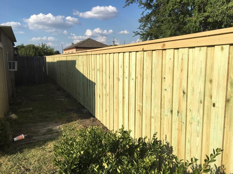 A wooden fence is in the backyard of a house.