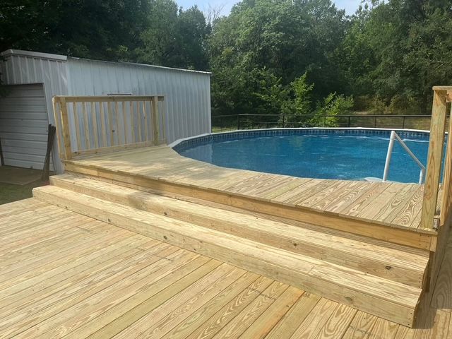 A wooden deck with a swimming pool in the background.