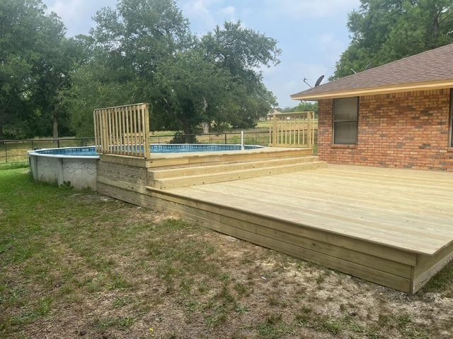 A wooden deck with a pool in the backyard of a house.