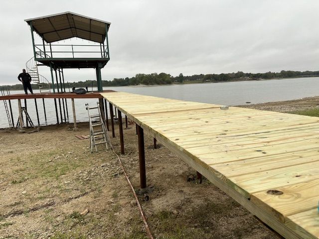 A man is standing on a wooden dock overlooking a lake.
