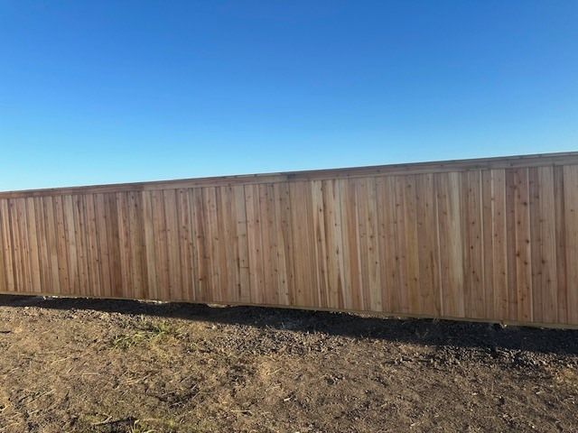 A wooden fence is sitting in the middle of a dirt field.
