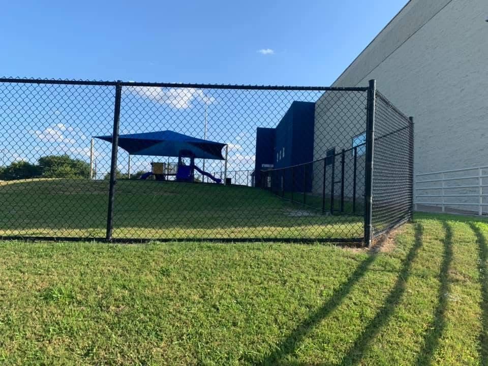 A chain link fence with a playground in the background