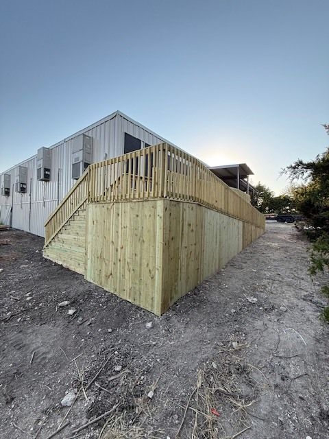 A wooden deck with stairs leading up to it is in front of a building.