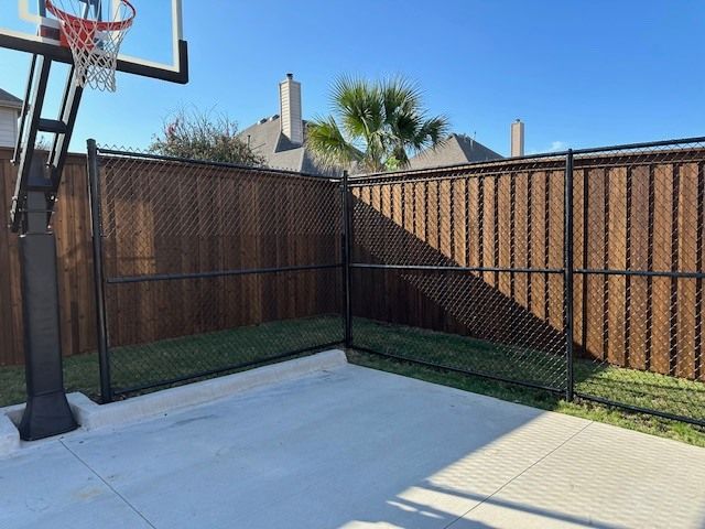 A basketball hoop is behind a chain link fence