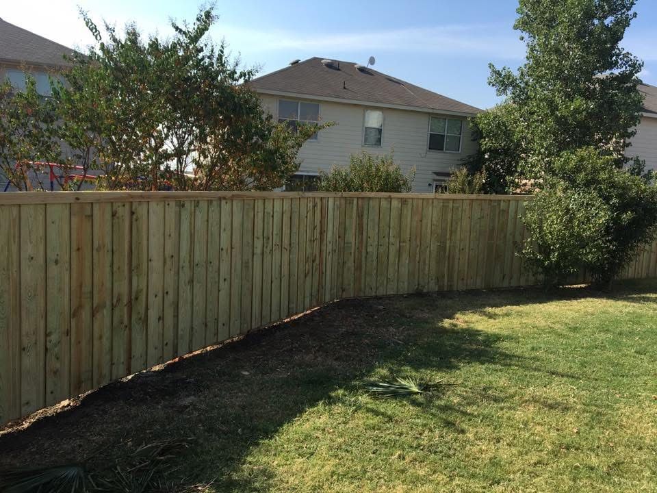 A wooden fence is in the backyard of a house.