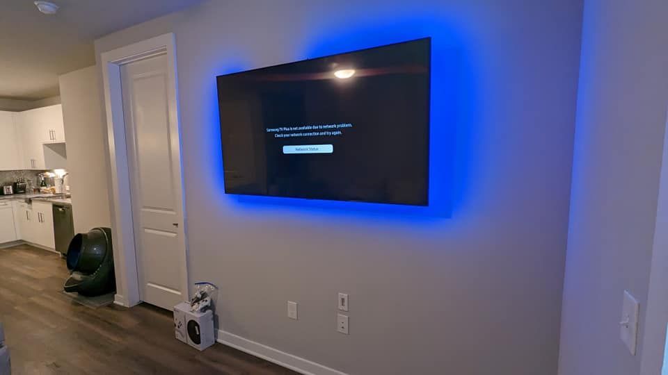 A flat screen tv mounted on a wall with blue lights around it.