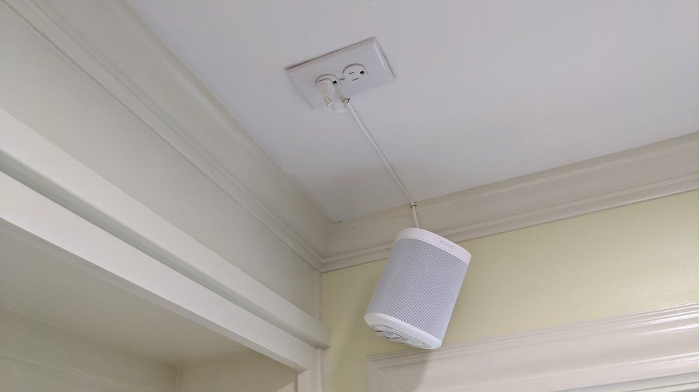 A speaker is hanging from the ceiling of a room next to a door.