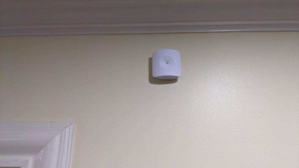 A white smoke detector is hanging on a wall next to a door.