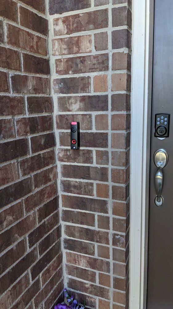 A doorbell is mounted on a brick wall next to a door.