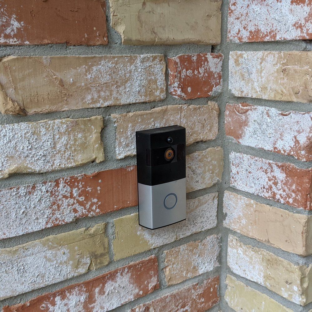 A doorbell is mounted on a brick wall.